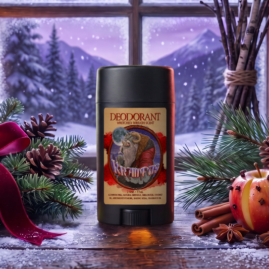 Krampus natural Deodorant stick in Evergreen Wreath, Pine Boughs and Spiced Apples scent on a snowy windowsill with pine boughs, cinnamon sticks, a red ribbon and clove-studded apples under a moonlit winter sky, Fable Beard Co.